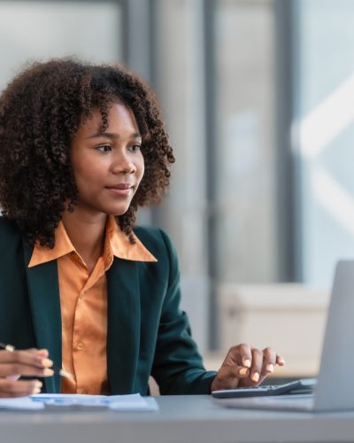 Online consult with laptop, video conference, Young pretty afric Online consult with laptop, video conference, Young pretty african american business woman bookkeepers working with balance sheet yearly reports to calculate tax and online consult in modern office.